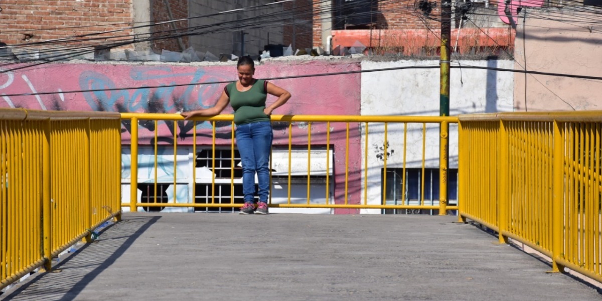 Una mujer descansa en la parte alta de un puente peatonal